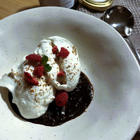 Dessert al cucchiaio con crema di cocco, crema di aglio nero UMAMI, lamponi essiccati e foglia di menta