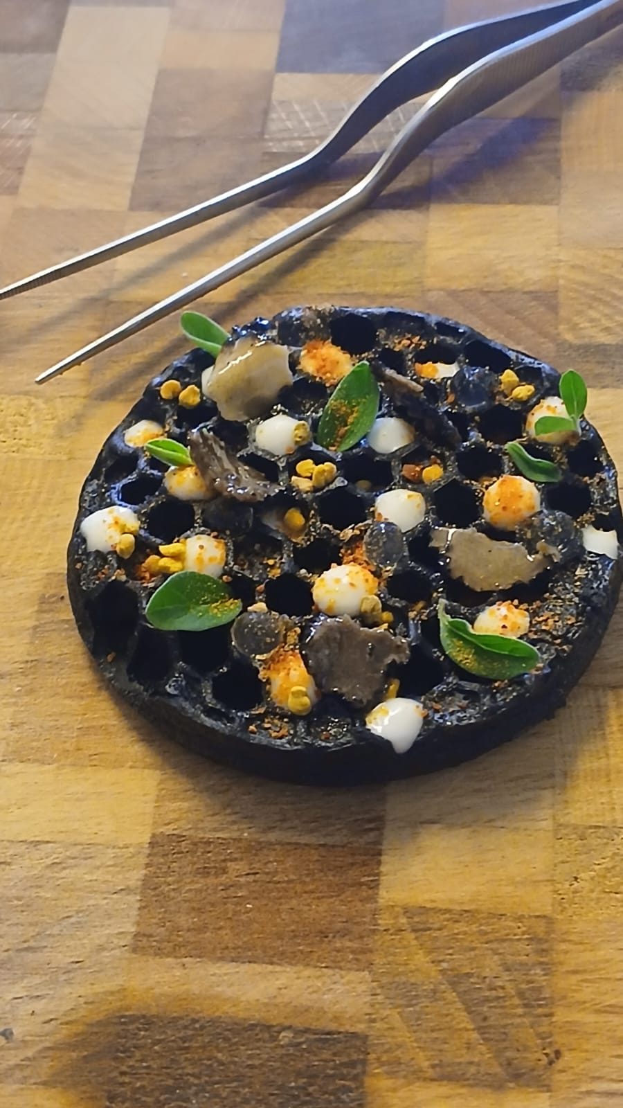 Cialda al carbone vegetale con crema di stracchino, tartufo e perle al rosmarino