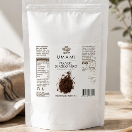 Polvere di aglio nero Umami con cucchiaio di prodotto su superficie in legno, ingrediente naturale per arricchire i piatti