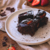 Brownies al cioccolato fondente con fragole fresche e polvere di aglio nero su piatto rustico