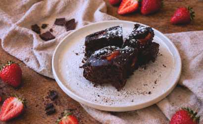 Brownies al cioccolato fondente con fragole fresche e polvere di aglio nero su piatto rustico