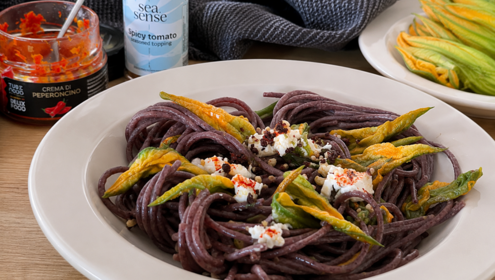Piatto di spaghetti ai fiori di zucca con caprino, Crema di Peperoncino e Topping Sea.Sense al Pomodoro.