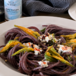 Piatto di spaghetti ai fiori di zucca con caprino, Crema di Peperoncino e Topping Sea.Sense al Pomodoro.