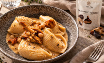Conchiglioni con crema di ceci e finferli in un piatto fondo, accanto alla confezione di aglio nero a spicchi UMAMI.